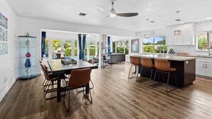A modern kitchen with a central island, wooden flooring, and a dining area with chairs. - Fort Lauderdale~River Access~Kayaks~Heated Pool (Fort Lauderdale)