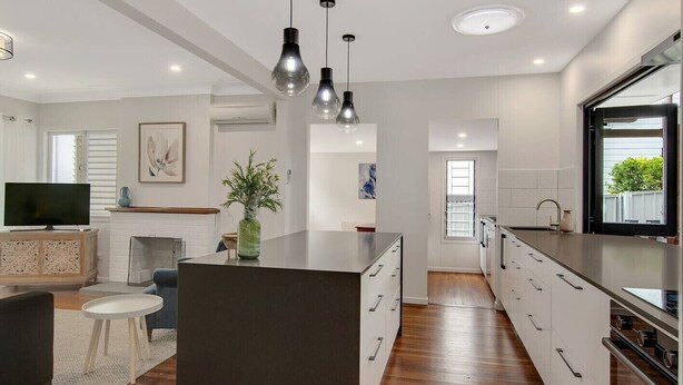 A modern kitchen with a central island, wooden flooring, and pendant lighting. - Modern family home in a leafy riverside suburb  (Graceville)