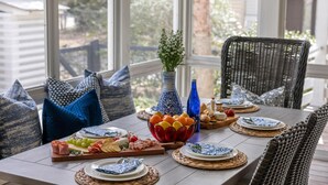 Een eettafel gedekt met blauw-witte borden, een fruitschaal en diverse soorten eten.