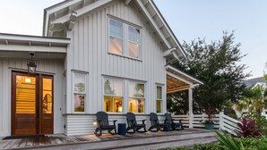 Een huis met twee verdiepingen, een veranda, houten trappen en een witte hek.