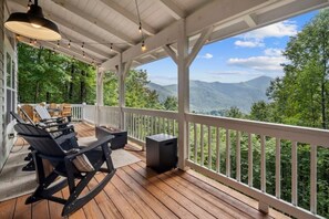 A wooden deck with a white railing, outdoor furniture, and a view of mountains. - Smokey Mtn Retreat: YEAR-ROUND VIEWS! GAME ROOM! HOT TUB! GOLF & SKI NEARBY! (Maggie Valley)