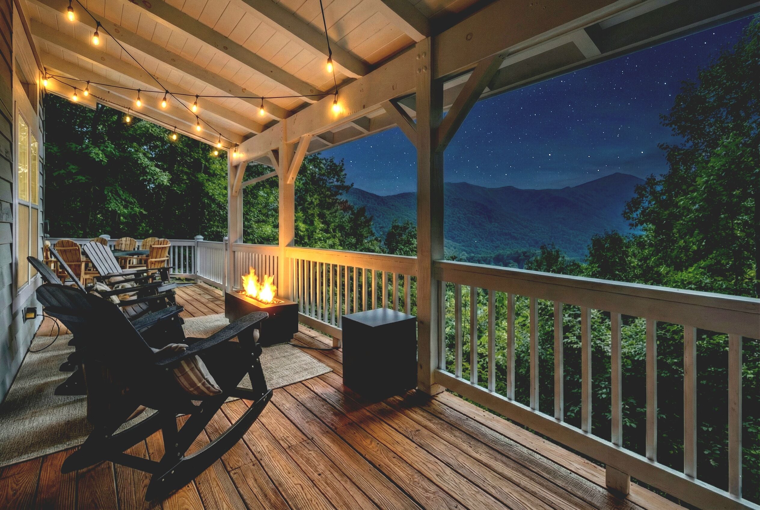 Une terrasse extérieure couverte, dotée d’un plancher en bois, de sièges et de guirlandes lumineuses.