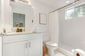 Et moderne badeværelse med et hvidt skab, toilet og bruseområde.