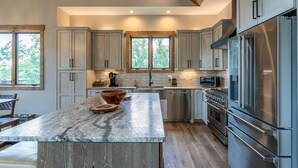 Una cocina moderna con una isla grande, electrodomésticos de acero inoxidable y armarios de madera.
