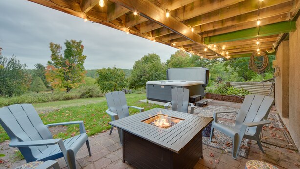 Patio esterno con poltrone Adirondack, un braciere e una vasca idromassaggio.