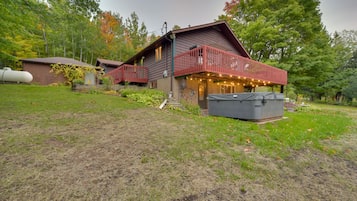 Un chalet rustique avec un balcon rouge, un espace salon extérieur abrité et un grand réservoir d’eau en arrière-plan.