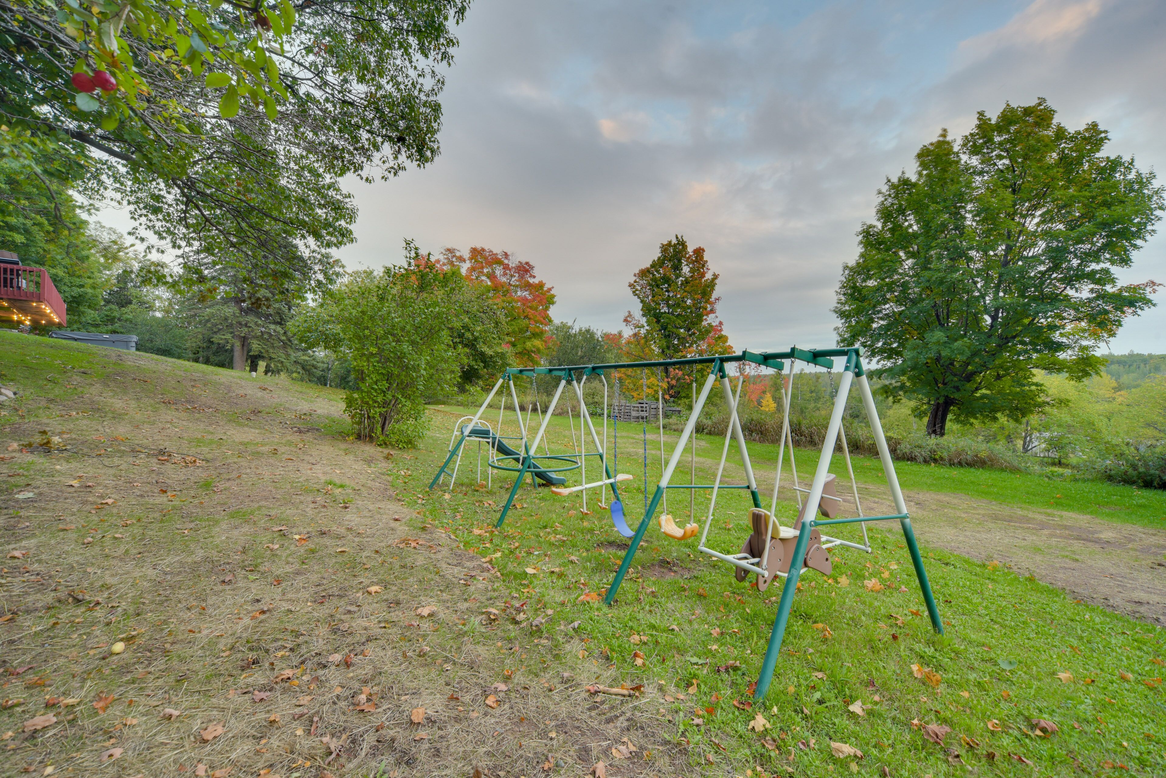 A swing set in a grassy area with trees and a building in the background.