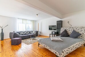 Un dormitorio moderno con una cama grande, un sofá, un televisor y una ventana.