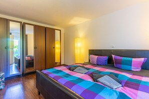 Un dormitorio con una cama grande, un armario de madera y vistas a un jardín.