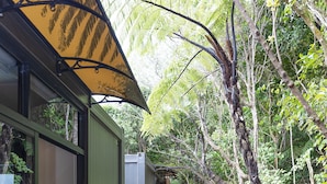 Une terrasse en bois avec un jacuzzi, entourée d’une clôture en bois et d’une végétation luxuriante.