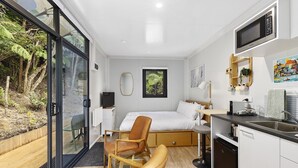 Une chambre moderne équipée d’un lit, d’un bureau, d’une chaise, d’un four à micro-ondes et offrant une vue sur l’extérieur.