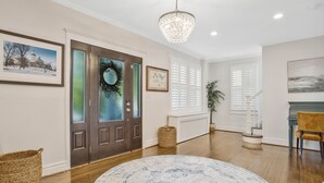 A spacious foyer with a wooden floor, a large round rug, a chandelier, and a staircase leading to another level. - Historic Annapolis Charmer <1Mile to NMC Stadium (Annapolis)