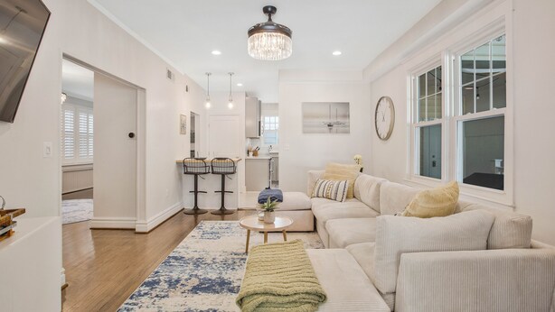 A spacious living room with a large sofa, a coffee table, and a chandelier. There is a kitchen in the background with a dining area. - Historic Annapolis Charmer <1Mile to NMC Stadium (Annapolis)