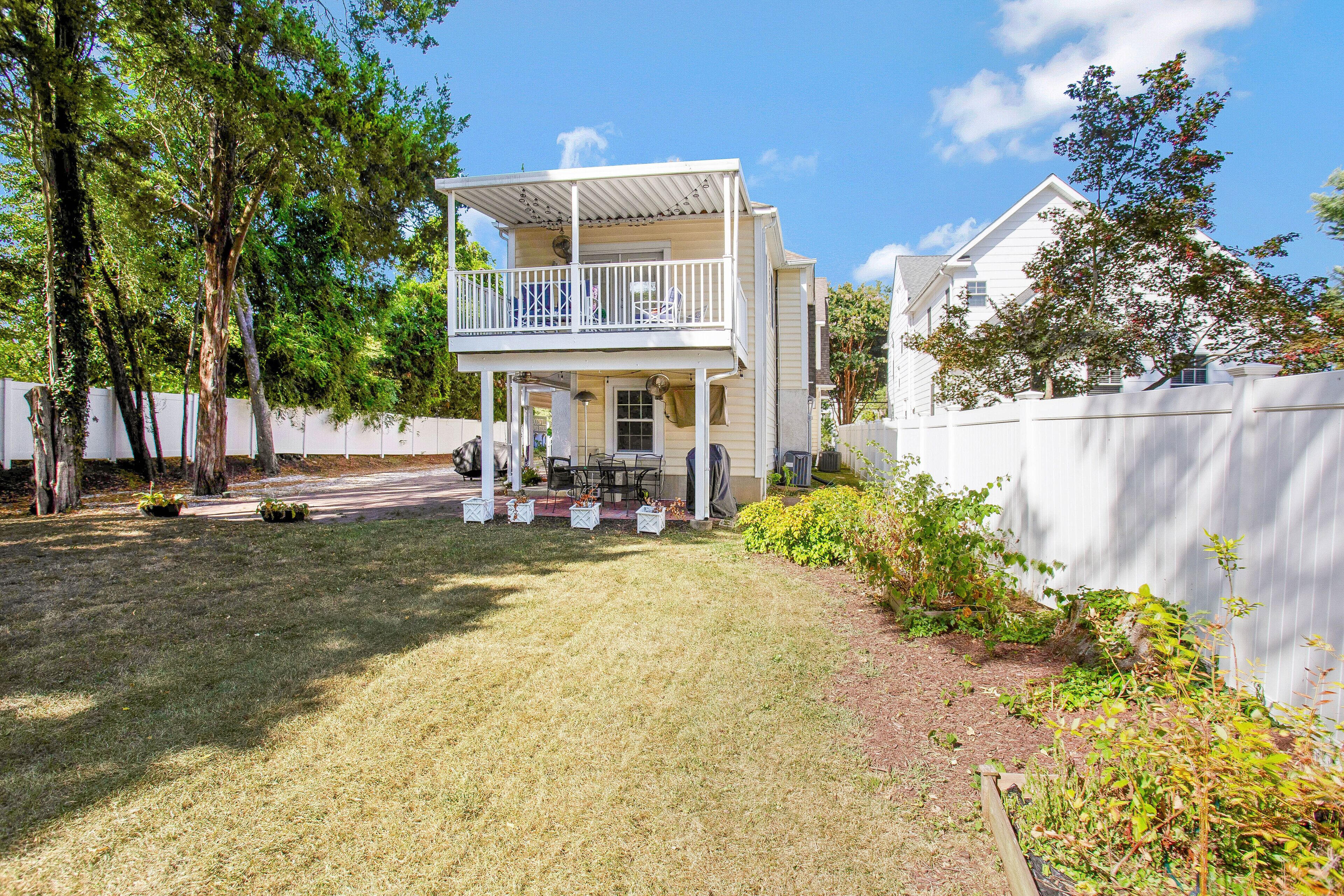 A two-story house with a balcony, a fenced yard, and a garden area.