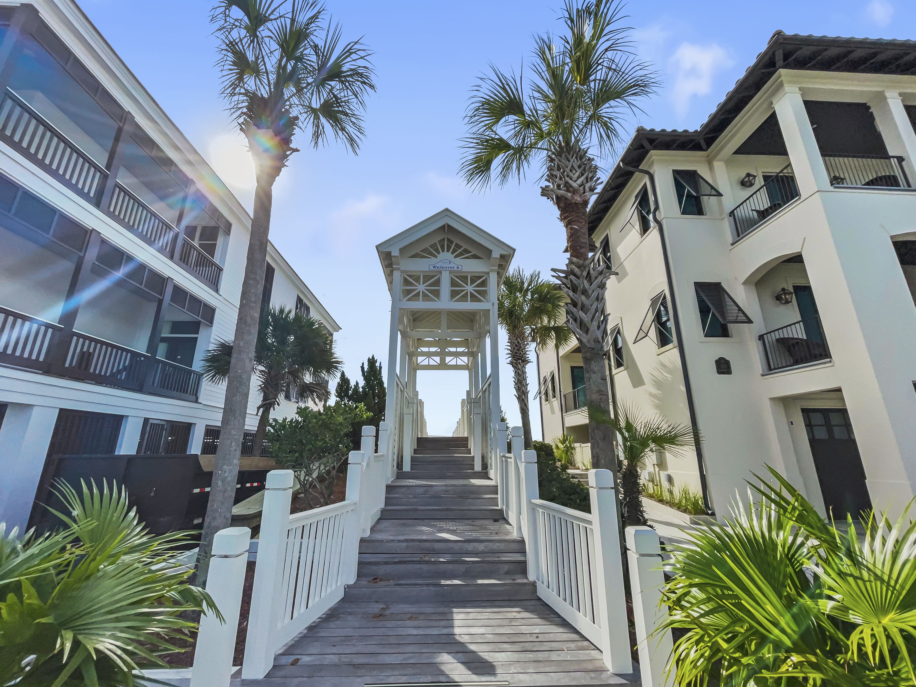 A wooden pathway leading to a gated entrance with a sign that reads "Welcome."