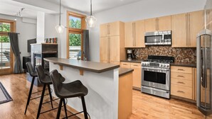 Une cuisine moderne avec des meubles en bois, des appareils électroménagers en acier inoxydable et un îlot central doté de tabourets de bar.