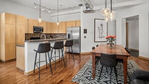 Une cuisine moderne avec des meubles en bois, un réfrigérateur en acier inoxydable et un îlot central doté de tabourets de bar.