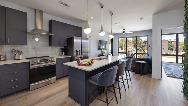 Una cocina moderna con una isla central, electrodomésticos de acero inoxidable e iluminación colgante.