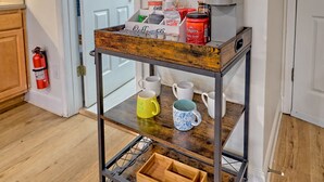 Eine Küchenarbeitsplatte mit einer Kaffeestation, darunter Tassen, Kaffeebohnen und eine Kaffeemaschine.