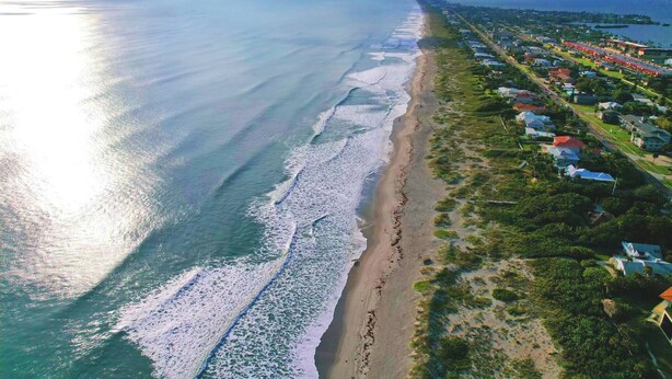 An aerial view of a coastal area with a beach and residential buildings. - Pool Paradise with hot tub, bikes, every beach need, games and more! (Cocoa Beach)