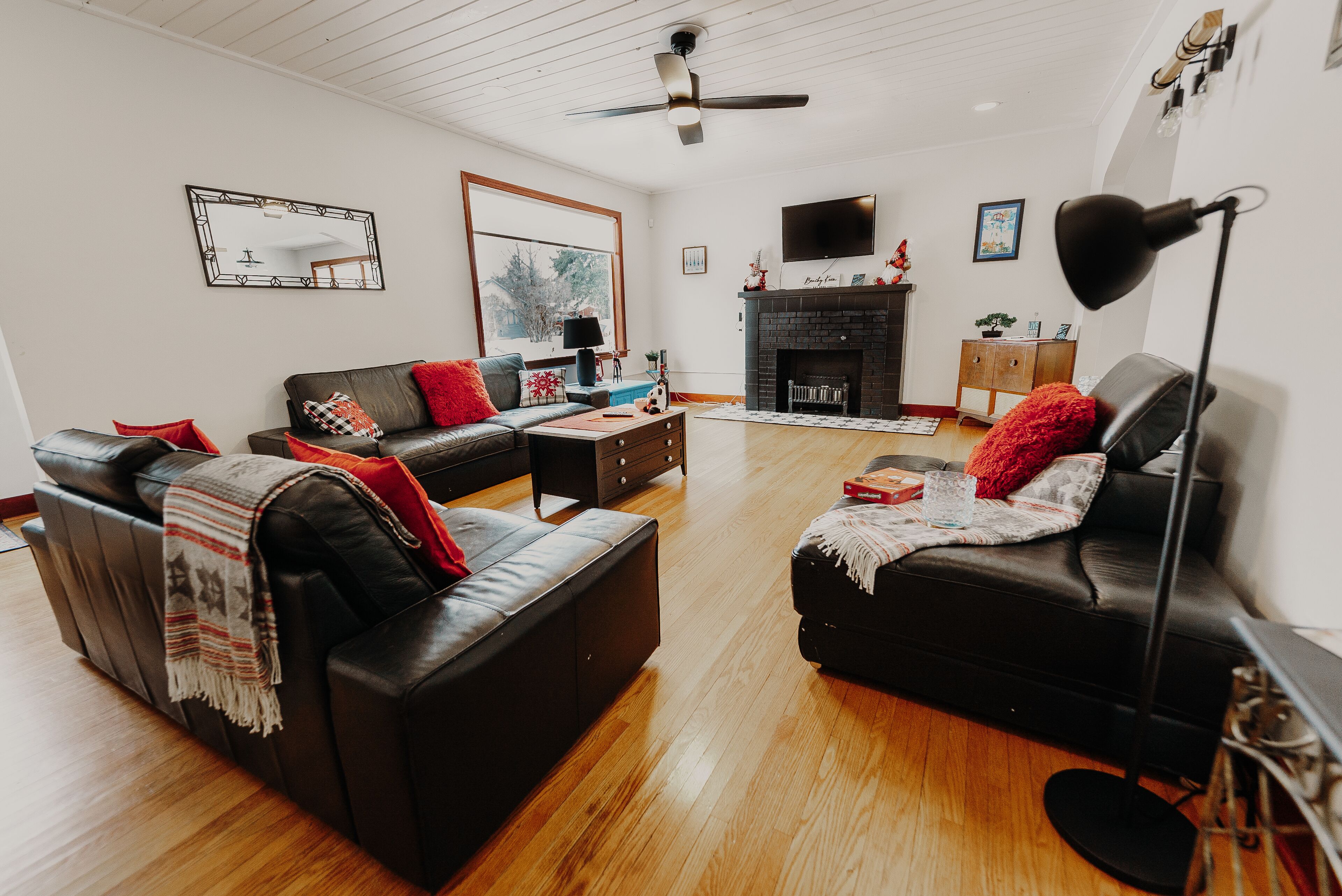 A modern living room with a fireplace, leather sofas, and a flat-screen TV.