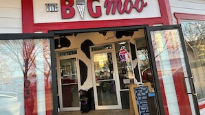 Die Schaufensterfront des Eiscafés The Big Moo mit einer Neonreklame und einer Kreidetafel-Speisekarte.