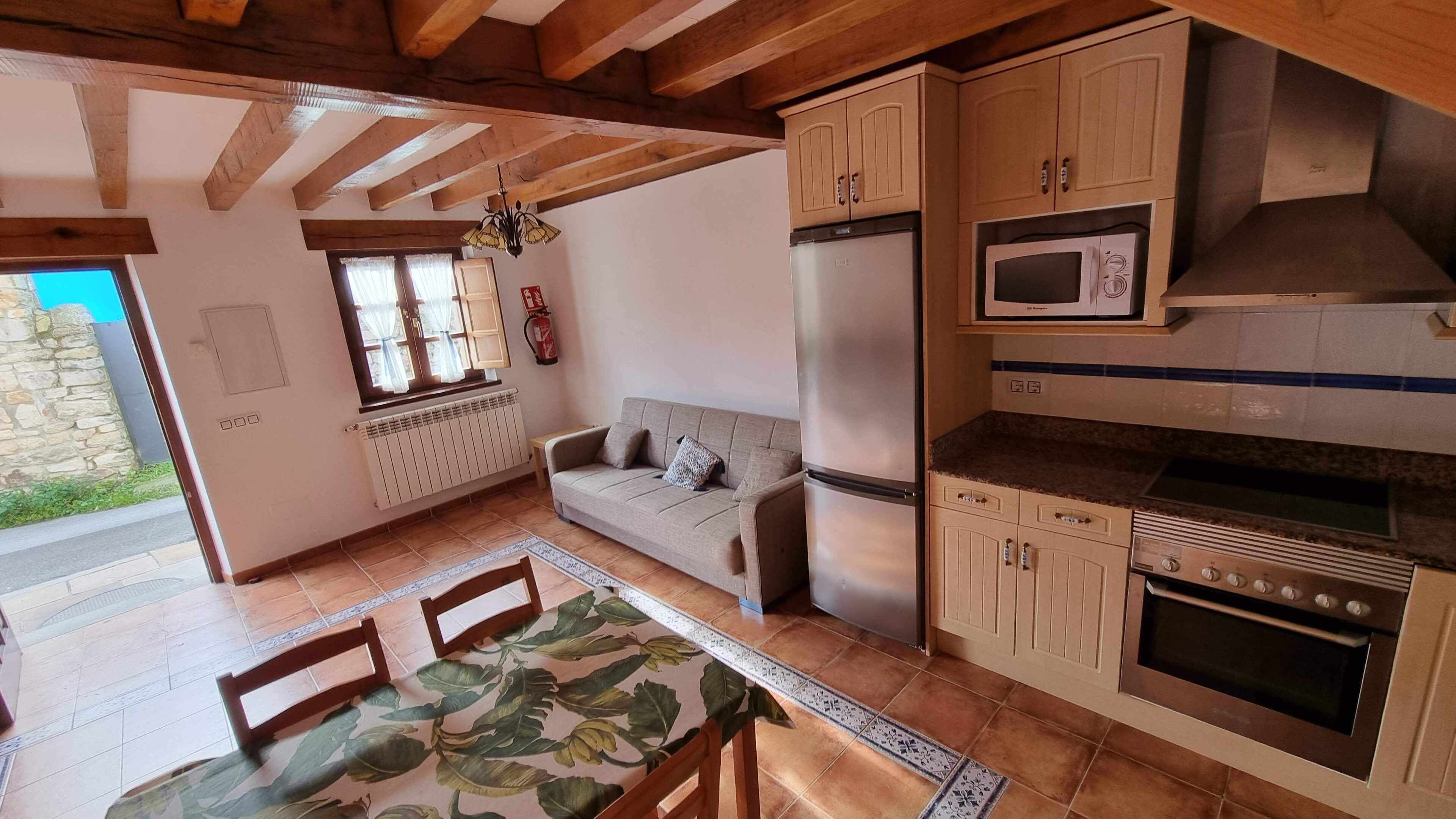 Une cuisine chaleureuse avec des poutres en bois, un canapé, une table à manger et un four encastré.