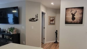 A modern kitchen with a dishwasher, a flat-screen TV, and a dining area with a wooden floor.