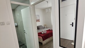 Ein Schlafzimmer mit einem Bett, einem Nachttisch, einem Spiegel und einer Tür zu einem Badezimmer.