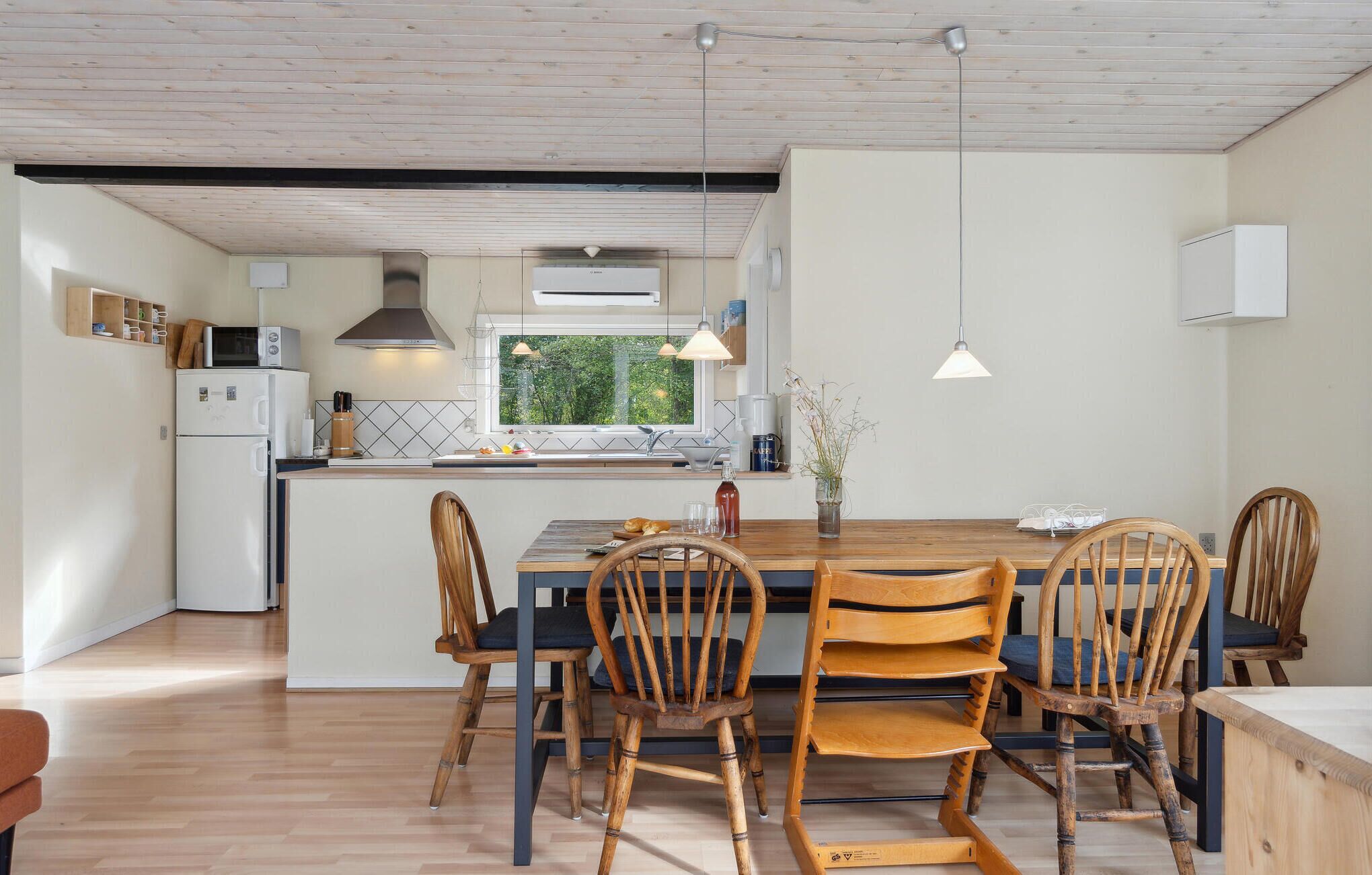 Une cuisine moderne dotée d’un îlot central, de chaises en bois et de luminaires suspendus.