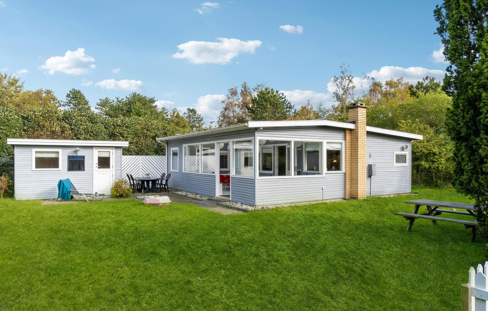 A mobile home with a patio area, a small shed, and a picnic table.