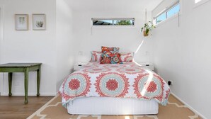 Un dormitorio con cama, una mesita y una planta colgante.