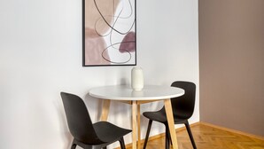 Et moderne værelse med et rundt hvidt bord, to sorte stole og en hvid vase på bordet.