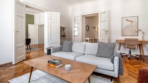 A modern living room with a grey sofa, a coffee table with books and a cup, wooden flooring, and a desk with a chair. - Terrific Landstraße 2BR w/ Elevator, nr Tram & Dining, by Blueground (Vienna)