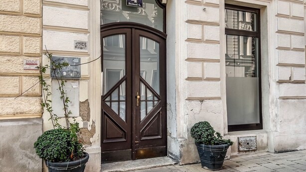 A building with a dark brown door, a sign reading "4 Bechard-G.", and two potted plants on the sidewalk. - Terrific Landstraße 2BR w/ Elevator, nr Tram & Dining, by Blueground (Vienna)
