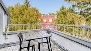 A balcony with a table and chairs, overlooking a red building and trees. - Airy Döbling 3BR w/ Balcony & Elevator, nr Restaurants, by Blueground (Vienna)