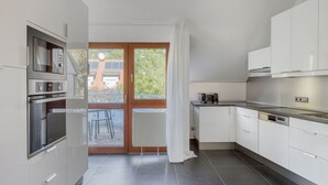 A modern kitchen with white cabinets, a built-in oven, and a large window with a view of the outside. - Airy Döbling 3BR w/ Balcony & Elevator, nr Restaurants, by Blueground (Vienna)