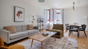 A modern living room with a sofa, armchair, coffee table, and dining area with chairs. - Airy Döbling 3BR w/ Balcony & Elevator, nr Restaurants, by Blueground (Vienna)