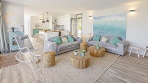 A modern living room with a grey sofa, round wooden coffee tables, and a large wave painting on the wall. - Casa del Mar · Pool & Sea Views · 10 Guests (Santa Margalida - Can Picafort/Son Serra Marina)