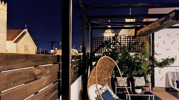 A cozy outdoor seating area with a wicker chair, a small table, and a potted plant. - Spectacular duplex with private terrace (Sevilla)