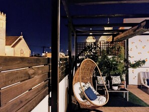 A cozy outdoor seating area with a wicker chair, a small table, and a potted plant. - Spectacular duplex with private terrace (Sevilla)