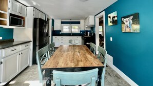 Une cuisine moderne avec des meubles blancs, une table à manger en bois et des murs de couleur turquoise.