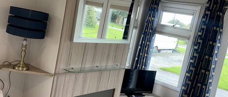 A modern kitchen with a built-in oven, a TV, and a window with curtains.