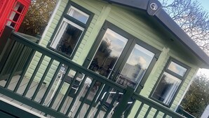 Un edificio pequeño de una sola planta con techo verde y detalles blancos, que cuenta con un balcón con barandilla verde.