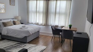 Ein modernes Schlafzimmer mit Bett, Nachttisch, Lampe und Schreibtisch mit Stühlen.