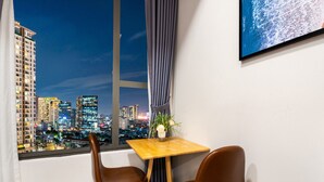 Ein Zimmer mit Blick auf die Stadt, ein kleiner Tisch mit zwei Stühlen und ein Blumentopf.