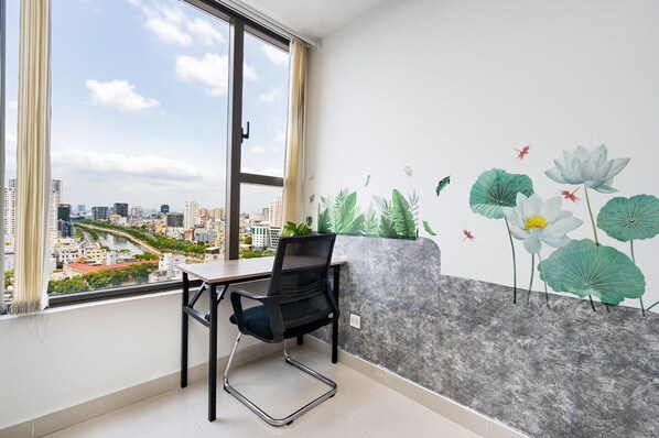 A modern office space with a large window, a desk, and a chair. A mural of lotus flowers and leaves adorns the wall.