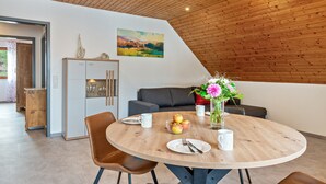 A dining area with a round table, chairs, a vase with flowers, and a painting on the wall. - Apartment "Panorama View" with Shared Garden, Balcony, and Wi-Fi (Salem)