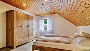 A bedroom with a wooden ceiling, a large wardrobe, a bed with two pillows, and a window with floral curtains. - Apartment "Panorama View" with Shared Garden, Balcony, and Wi-Fi (Salem)