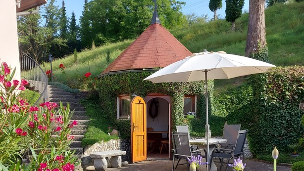 A patio area with a table and chairs, a white umbrella, and a stone bench. - Apartment "Panorama View" with Shared Garden, Balcony, and Wi-Fi (Salem)